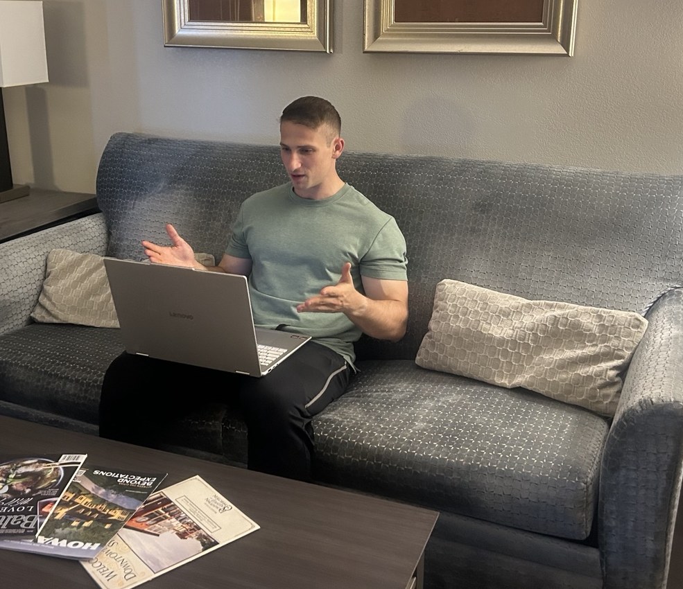 Jack Quint in a green T-shirt, speaking and gesturing while working at his laptop.